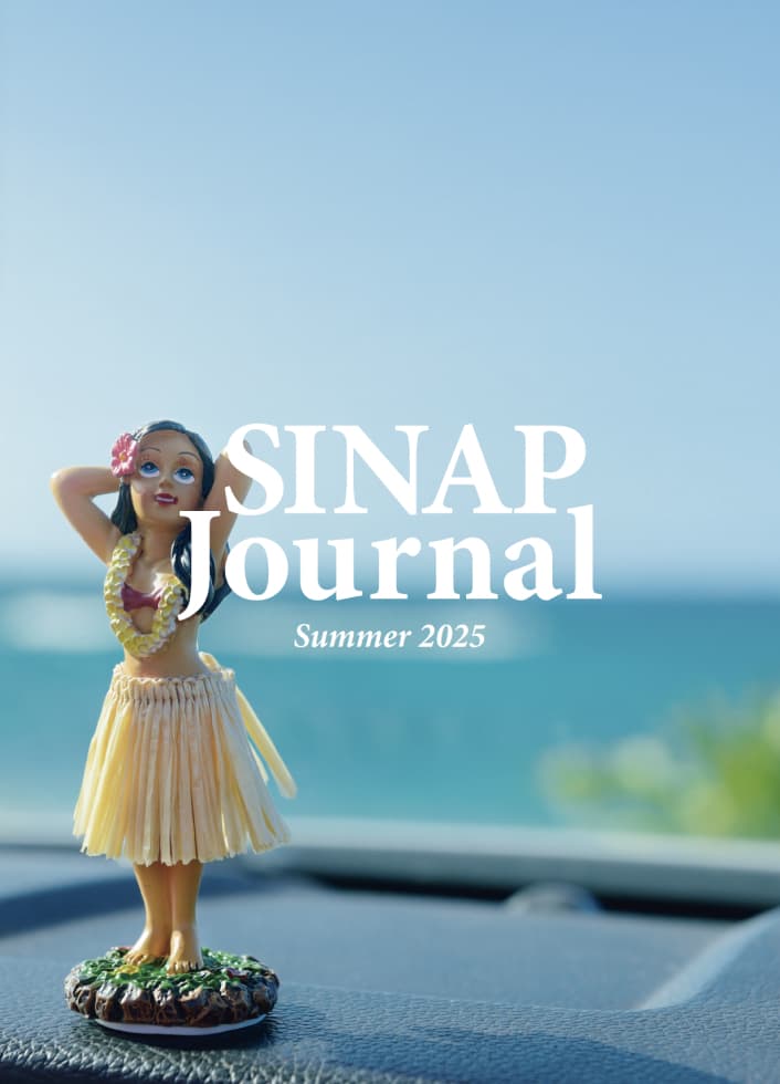表紙 SINAP Journal Summer 2025 フラダンサーの人形が車のダッシュボードに置かれ、背景に海が見える夏らしい写真